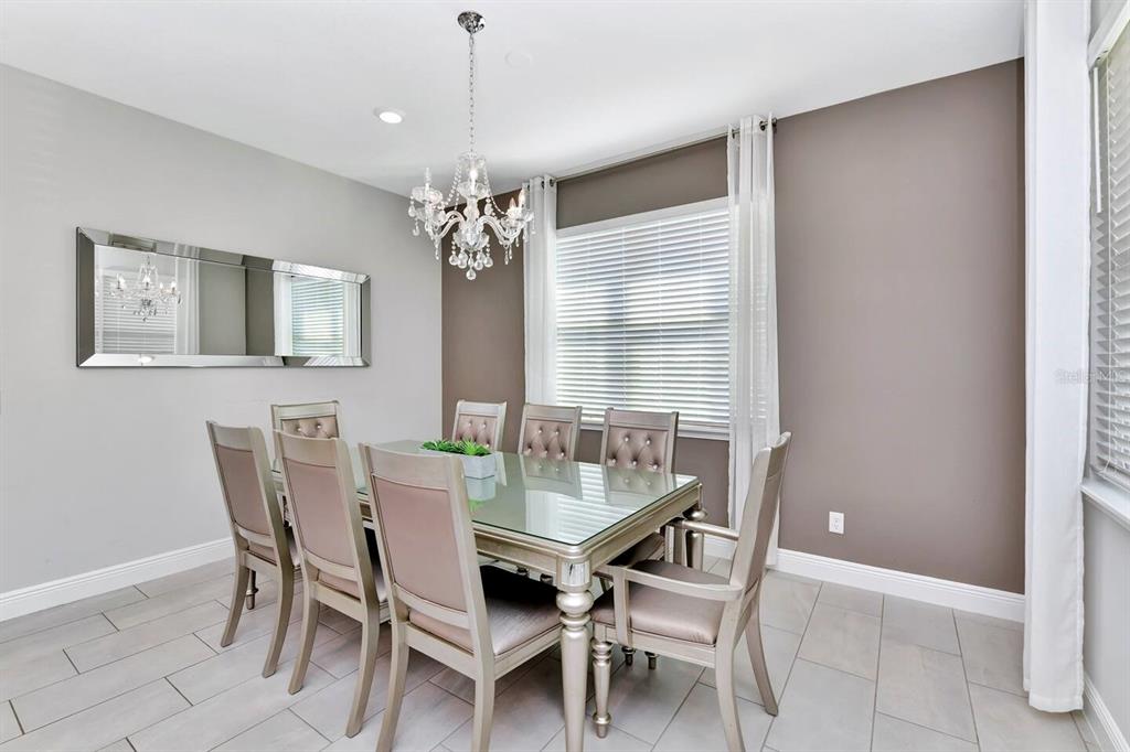 A dining room features a glass-topped table, six upholstered chairs, a chandelier, and a mirror — 253 SOUTHFIELD STREET, KISSIMMEE, FL
