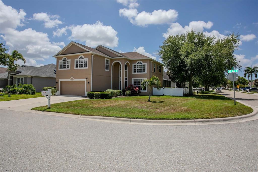 A two-story suburban house with a tan exterior, a two-car garage, and a corner lot — 3010 42ND AVENUE E, BRADENTON, FL