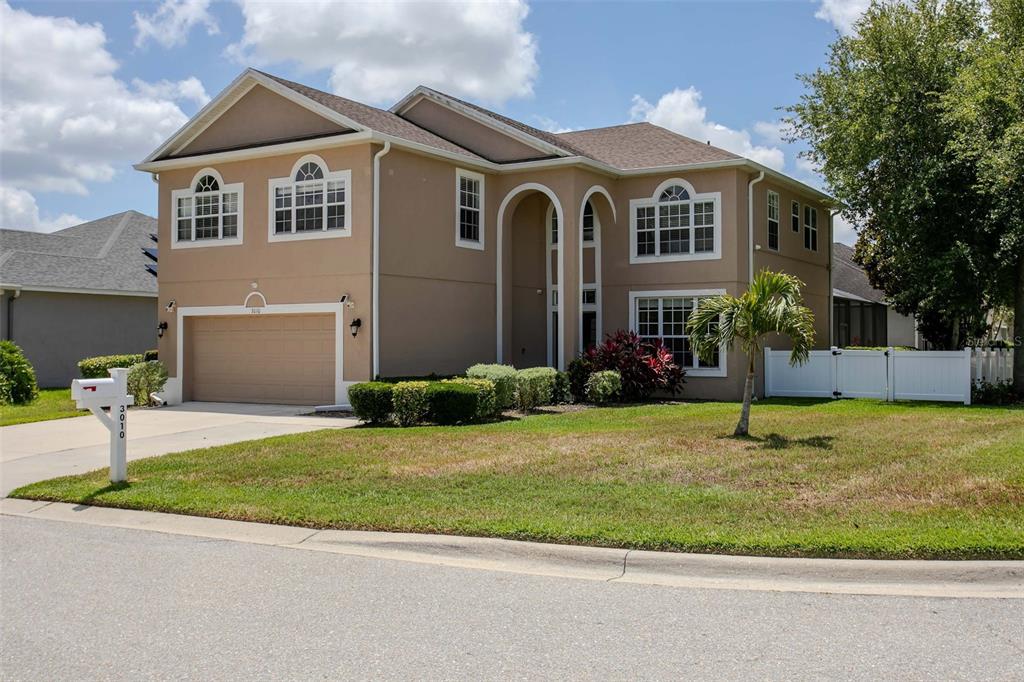 A two-story suburban house with a tan stucco exterior, a two-car garage, and arched windows — 3010 42ND AVENUE E, BRADENTON, FL