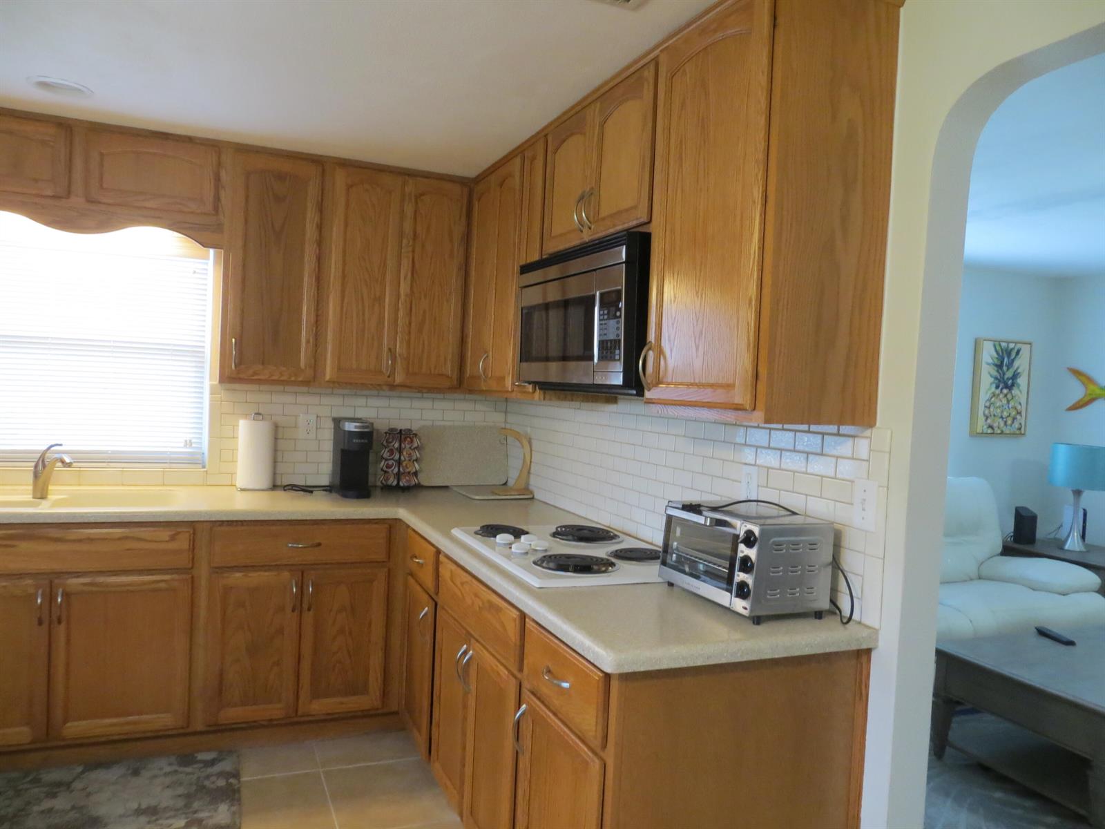 A kitchen features oak cabinets, a white subway tile backsplash, and a stainless steel microwave — 509 S Mccall Road, Englewood FL 34223, ENGLEWOOD, FL