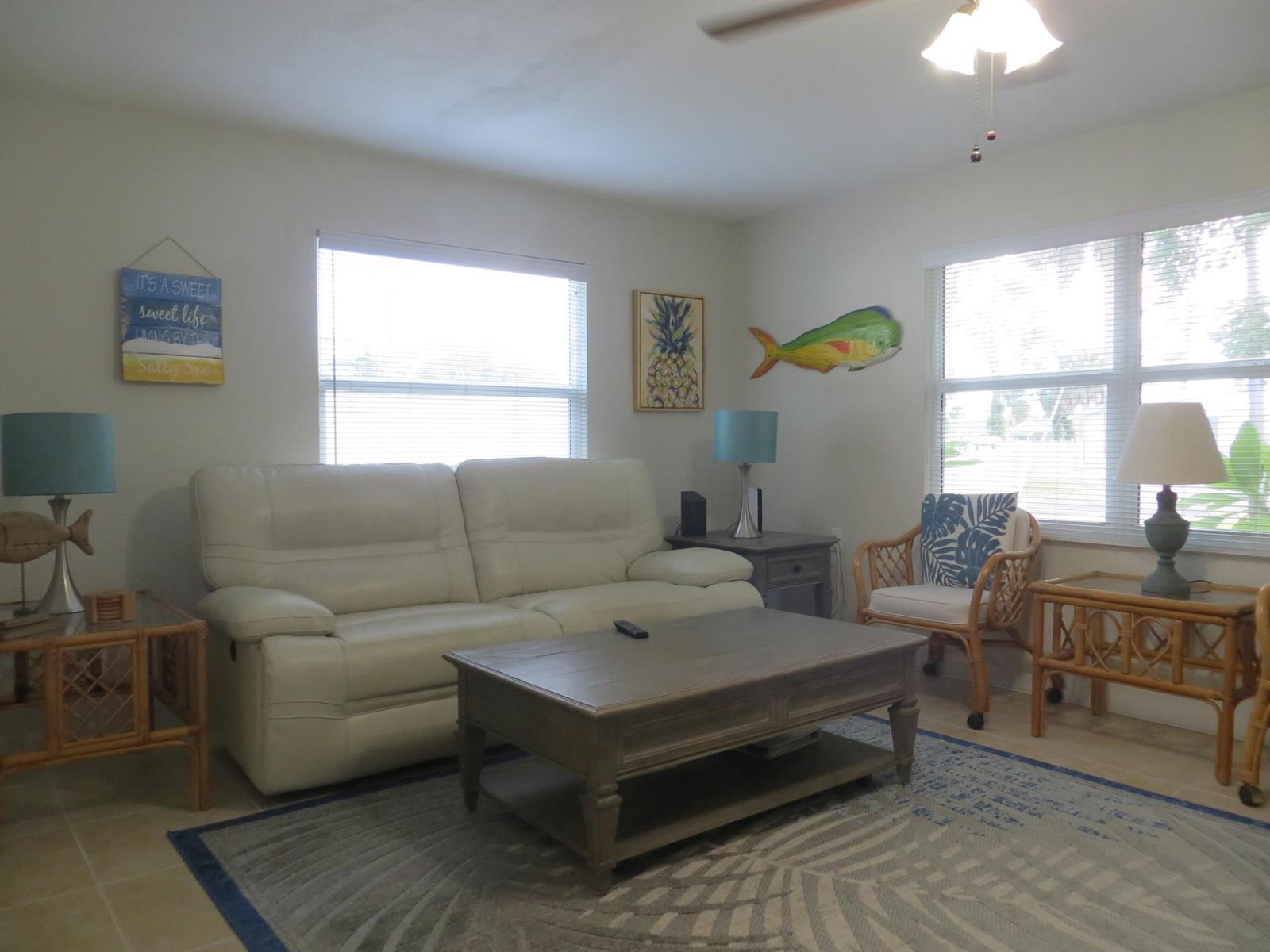 A living room featuring a white leather sofa, wooden coffee table, and coastal-themed decor — 509 S Mccall Road, Englewood FL 34223, ENGLEWOOD, FL