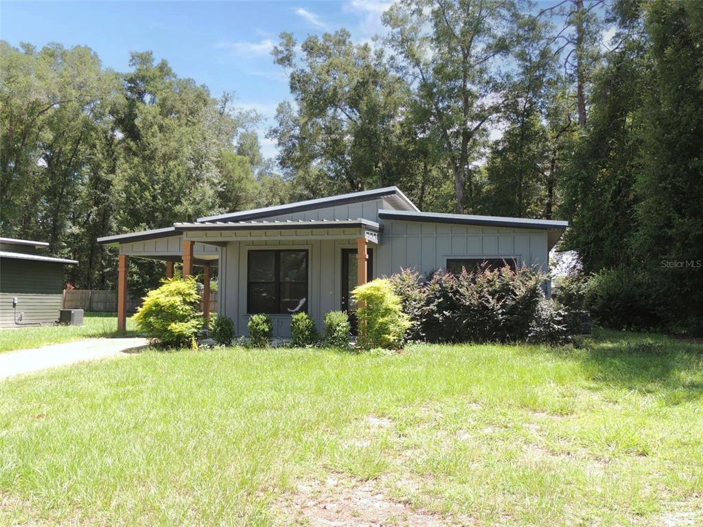 A gray, single-story house with a metal roof and a covered porch sits on grass — 7439 SE 78TH PLACE, TRENTON, FL