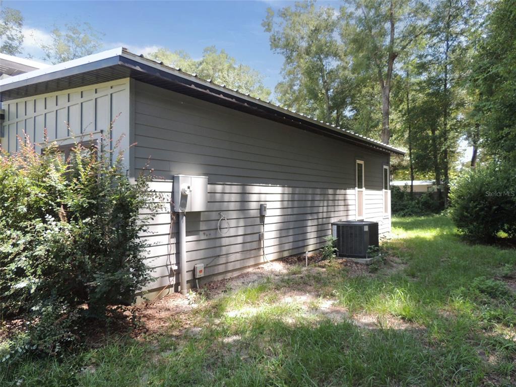 The exterior side of a gray house features horizontal siding, an electrical panel, and an AC unit — 7439 SE 78TH PLACE, TRENTON, FL