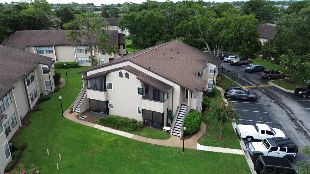A screened-in balcony with wood flooring overlooks a grassy courtyard and neighboring apartment buildings — 3019 ANTIQUE OAKS CIRCLE UNIT 124, WINTER PARK, FL