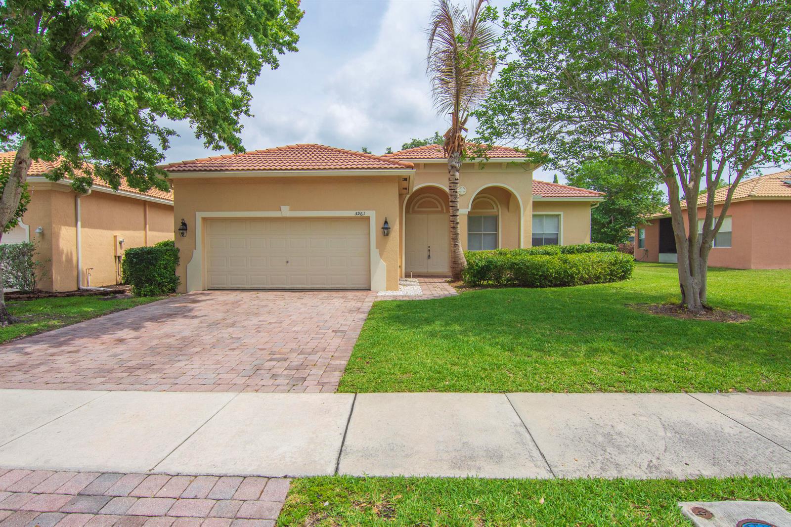 A single-story tan stucco house with a tiled roof, brick driveway, and front lawn — 5961 Spanish River Road, Fort Pierce FL 34951, FORT PIERCE, FL