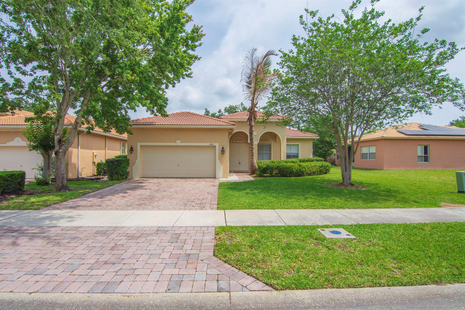 A single-story house with a tan stucco exterior, tile roof, and a paved driveway — 5961 Spanish River Road, Fort Pierce FL 34951, FORT PIERCE, FL