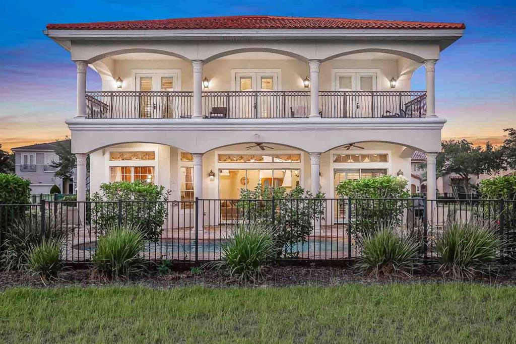 A two-story house with a tiled roof, arched balconies, and a fenced backyard pool — 7438 GATHERING COURT, REUNION, FL