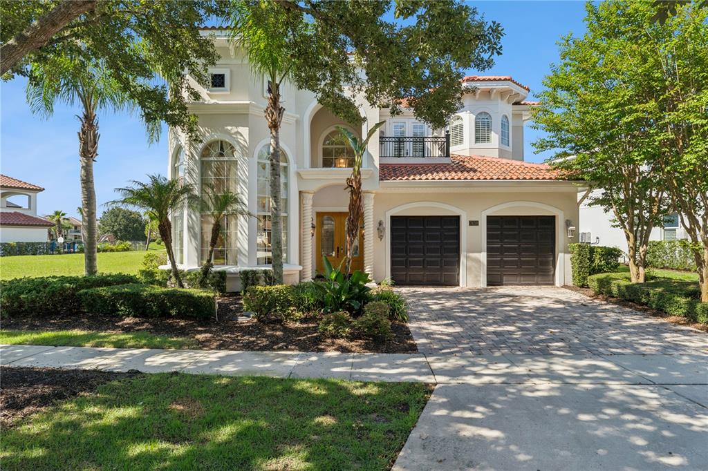 A two-story Mediterranean-style house features a tiled roof, arched windows, and a two-car garage — 7438 GATHERING COURT, REUNION, FL