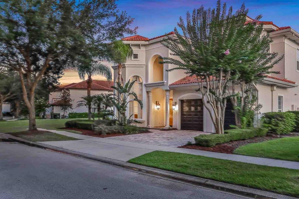 A two-story Mediterranean-style house with a tile roof, arched entryway, and a paved driveway — 7438 GATHERING COURT, REUNION, FL