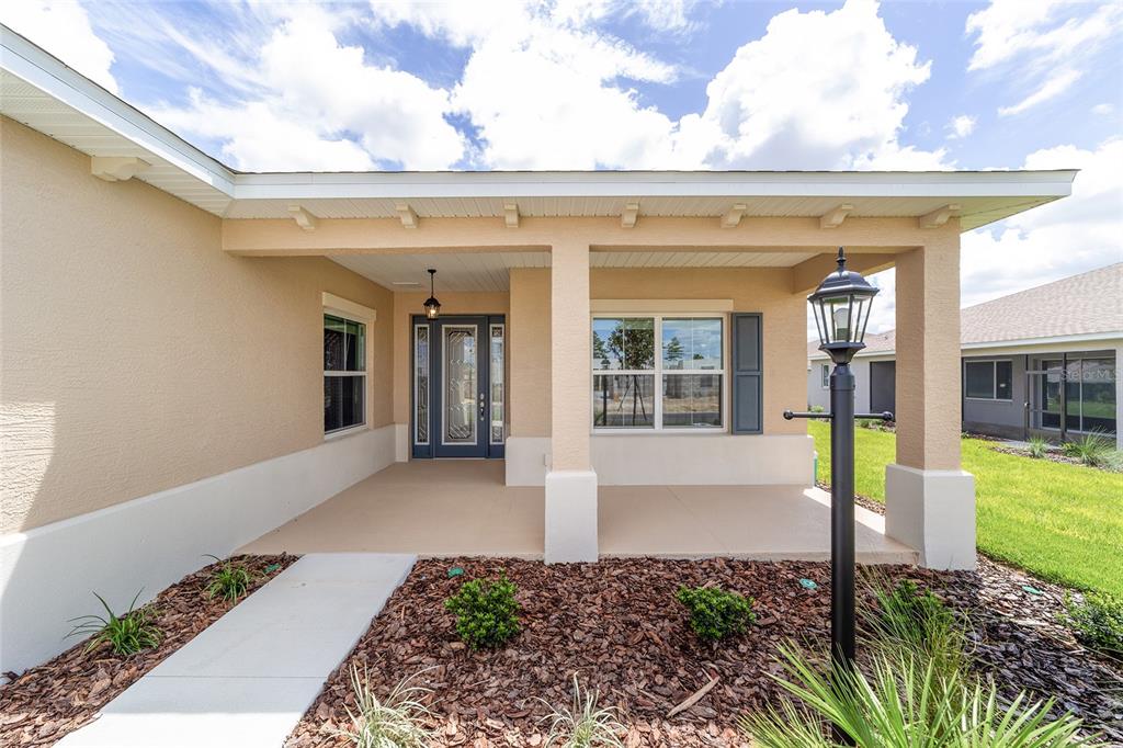 A covered front porch with a concrete walkway leads to a blue front door — 10135 SW 106TH CIRCLE, OCALA, FL