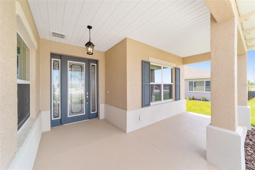 A covered front porch features a gray front door with glass inserts and shutters — 10135 SW 106TH CIRCLE, OCALA, FL