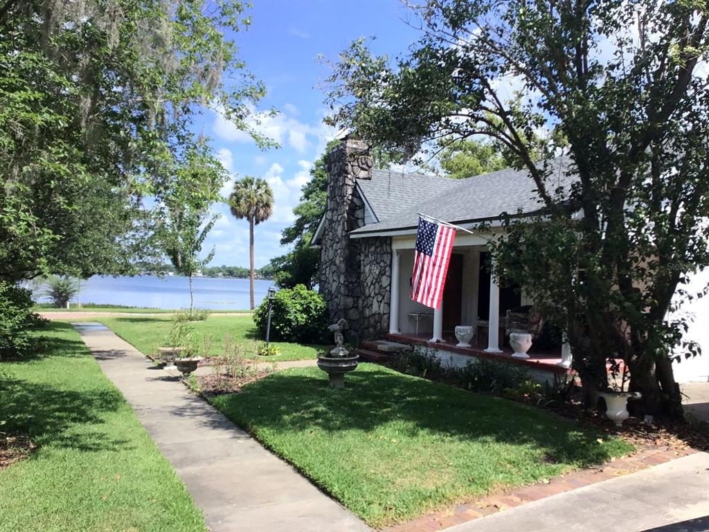 A stone-faced cottage with a front porch and American flag overlooks a lake — 120 BROADVIEW AVENUE, WINTER PARK, FL