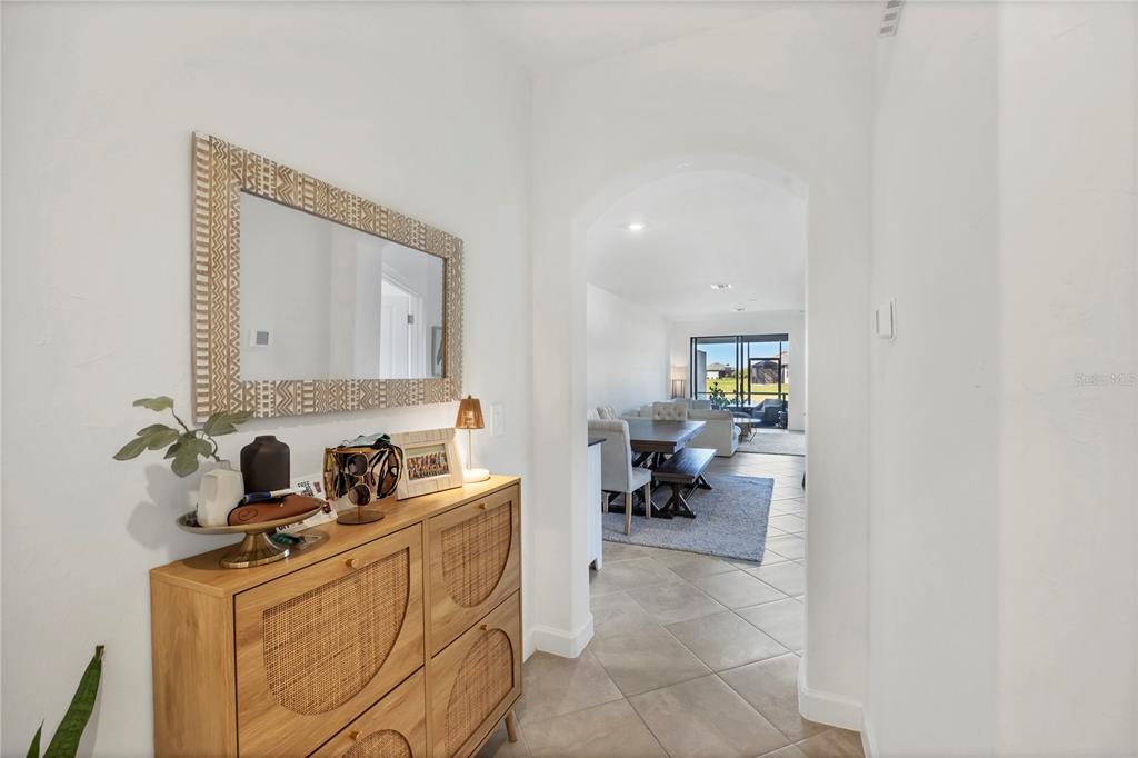 A hallway with a wooden cabinet and mirror leads into an open-concept living and dining area — 15733 SUNNY DAY DRIVE, BRADENTON, FL