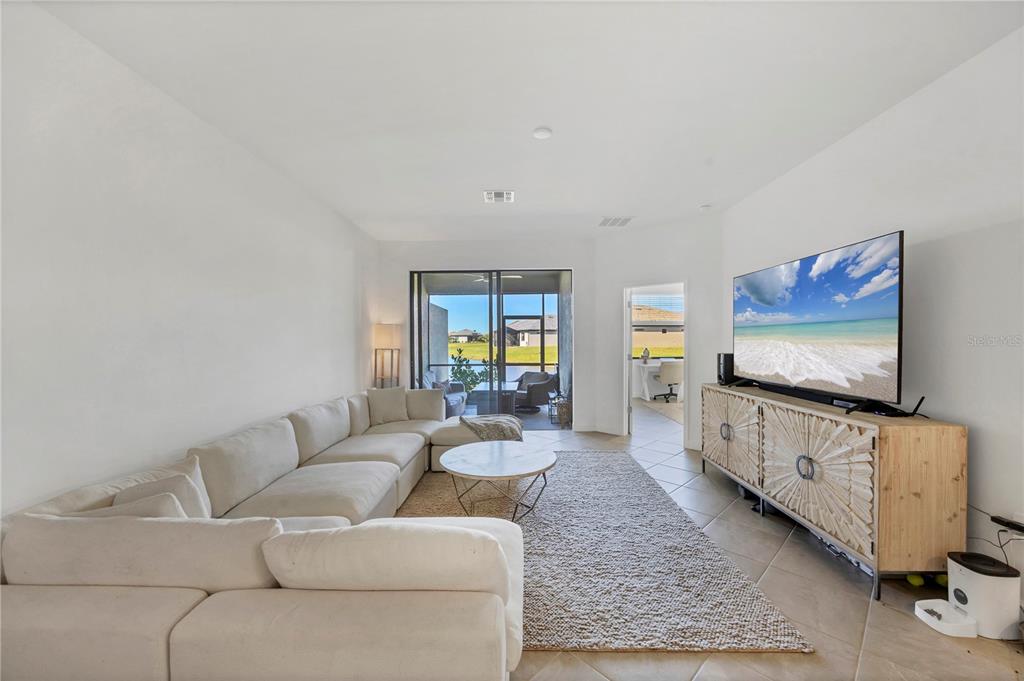 A living room features a large sectional sofa, a television on a console, and sliding doors — 15733 SUNNY DAY DRIVE, BRADENTON, FL