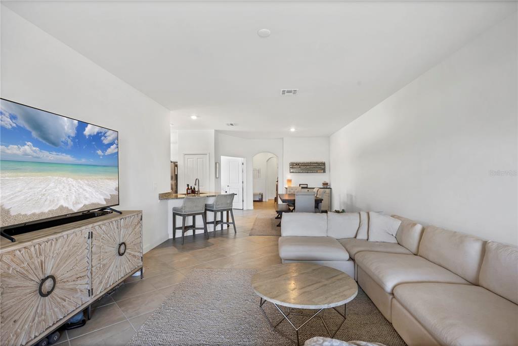A living room features a sectional sofa, a round coffee table, and a television console — 15733 SUNNY DAY DRIVE, BRADENTON, FL