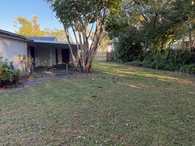 A grassy backyard features a large tree next to a house with a covered patio — 1310 FAIRVIEW AVENUE, WINTER PARK, FL