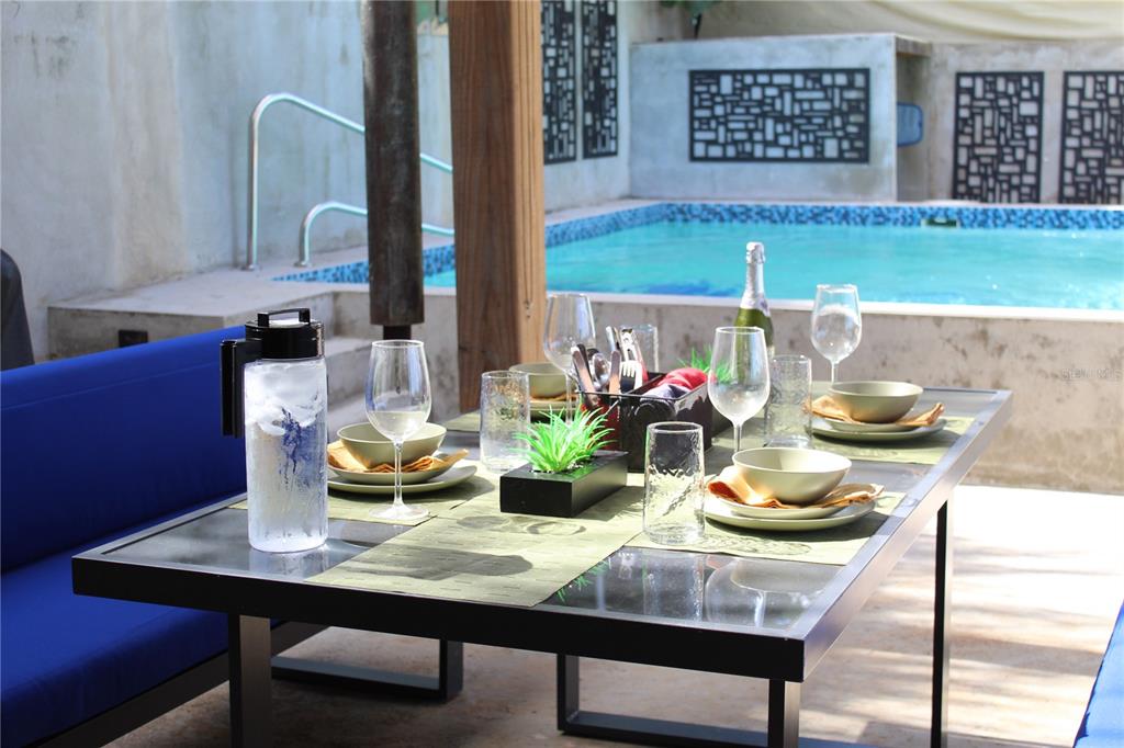 An outdoor dining table with place settings sits on a patio beside a swimming pool — 210 VISTA BELLA, VIEQUES, PR