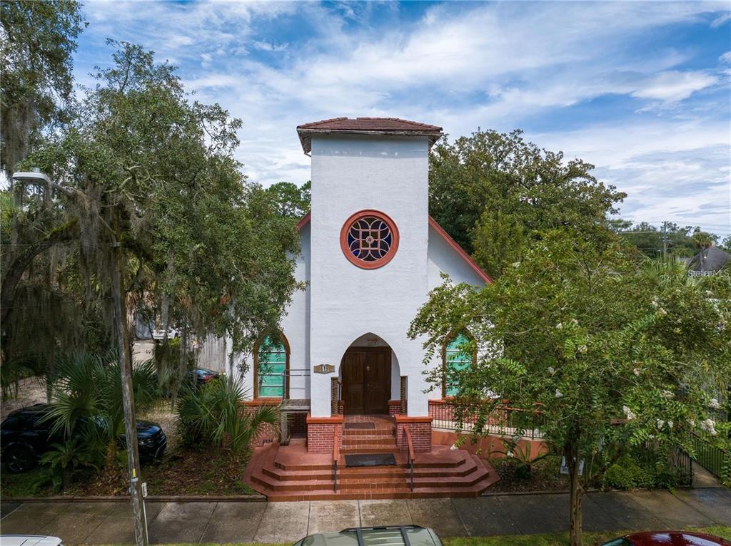 A white church building with a central tower, arched windows, and a brick entrance staircase — 619 NE 1ST STREET, GAINESVILLE, FL