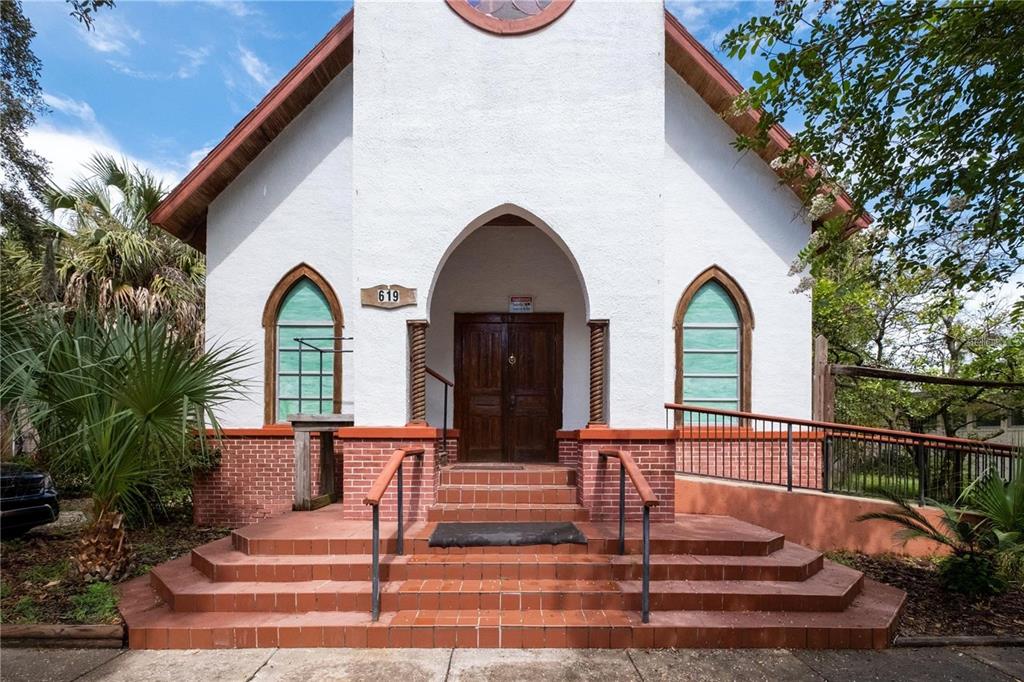 A white church building with a brick base, arched windows, and a central entrance staircase — 619 NE 1ST STREET, GAINESVILLE, FL