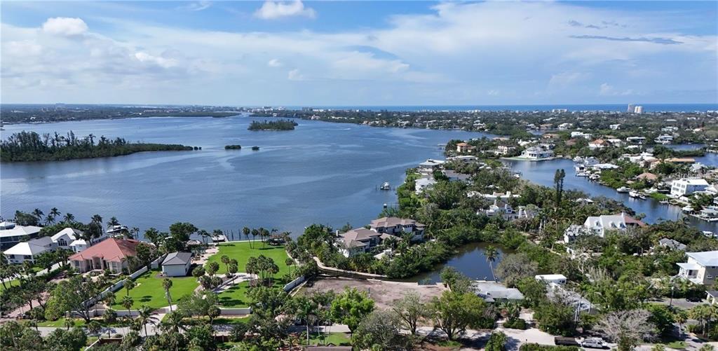 An aerial view shows waterfront homes, lush landscaping, and a large bay under a blue sky — 546 FREELING DRIVE, SARASOTA, FL