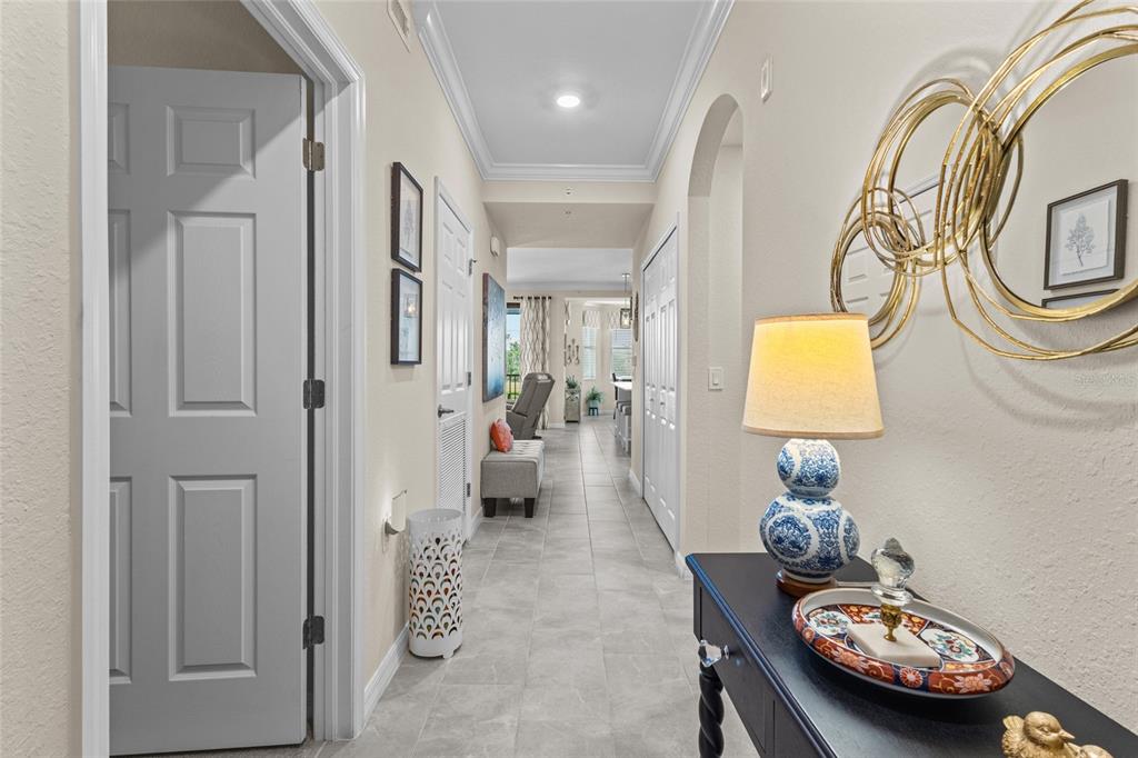 A hallway with tile flooring leads toward an open living area with a console table — 17626 GAWTHROP DRIVE UNIT 202, BRADENTON, FL