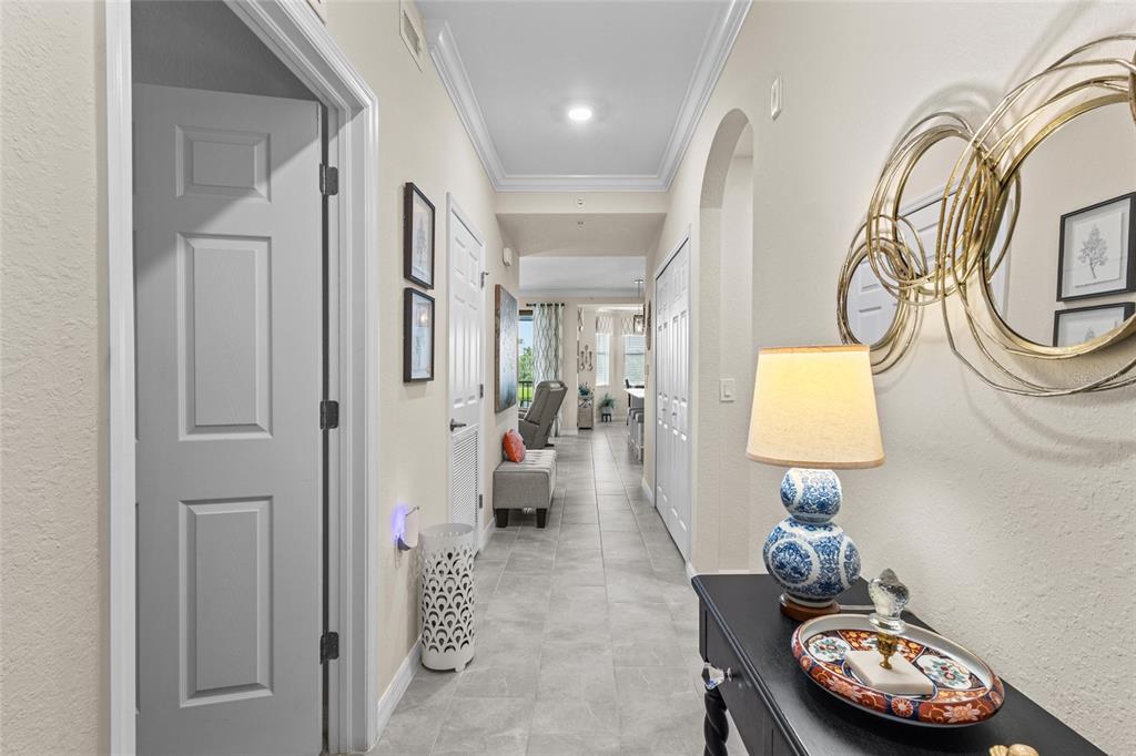 A hallway with tile flooring leads toward an open living area with a console table — 17626 GAWTHROP DRIVE UNIT 202, BRADENTON, FL