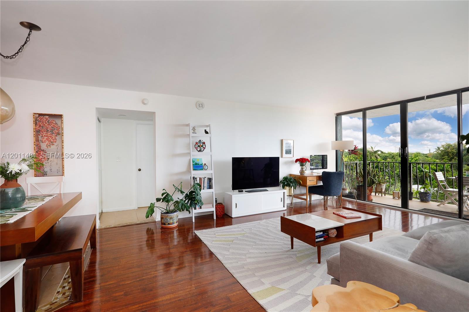 A living room features hardwood floors, a gray sofa, a coffee table, and a balcony view — 780 NE 69th St # 404, Miami FL 33138, MIAMI, FL
