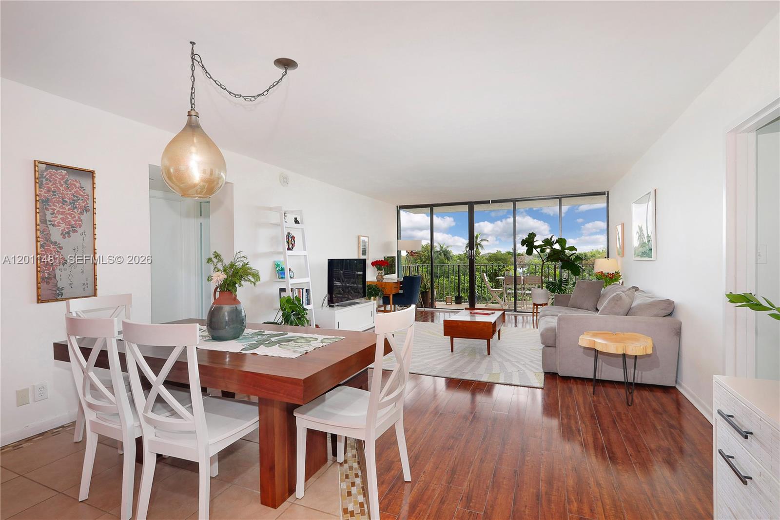 A dining area and living room with hardwood floors, white walls, and a balcony view — 780 NE 69th St # 404, Miami FL 33138, MIAMI, FL