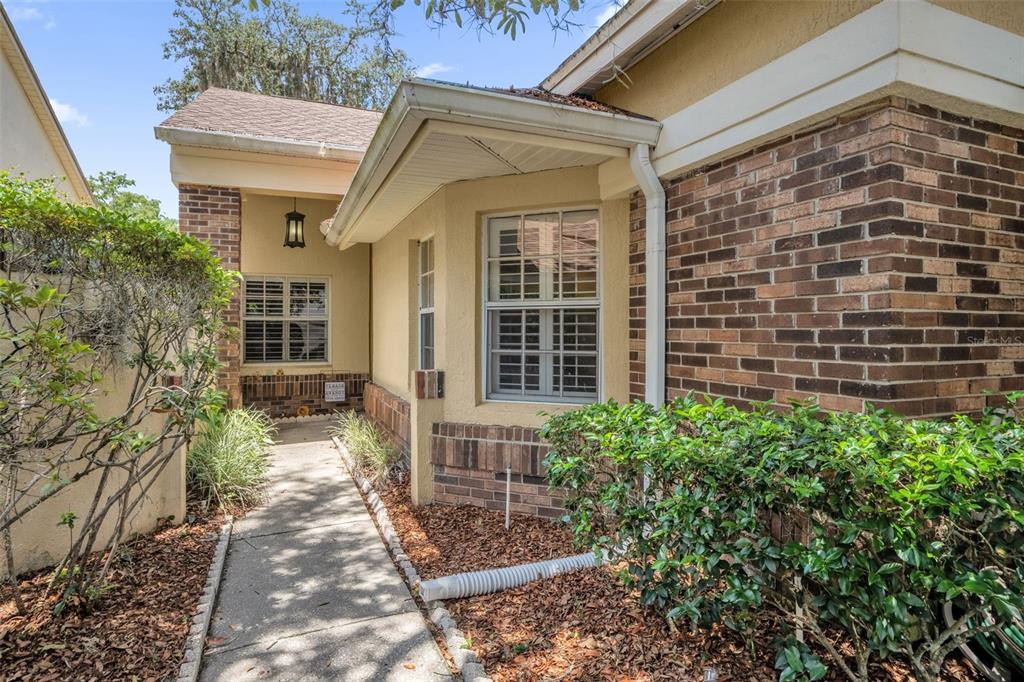 A concrete walkway leads to the entrance of a house with brick and stucco siding — 711 ANDOVER CIRCLE, WINTER SPRINGS, FL