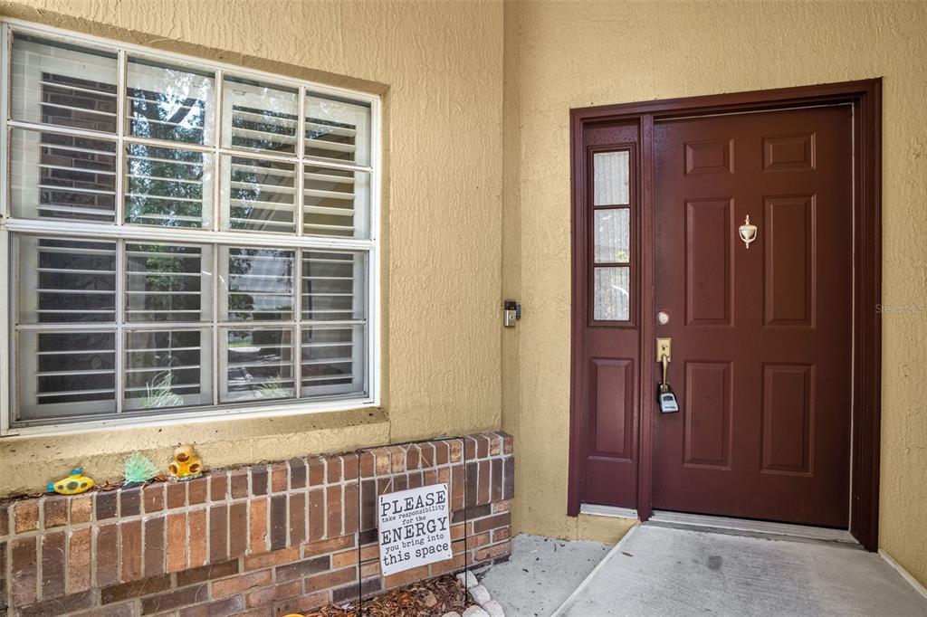 A brown front door with a side window and a window with shutters on the left — 711 ANDOVER CIRCLE, WINTER SPRINGS, FL