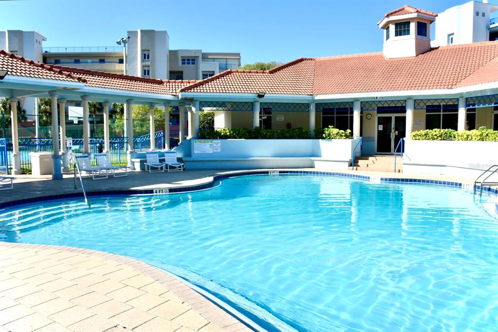 A swimming pool with a tiled deck sits in front of a building with a roof — 5300 S ATLANTIC AVENUE UNIT 8-302, NEW SMYRNA BEACH, FL