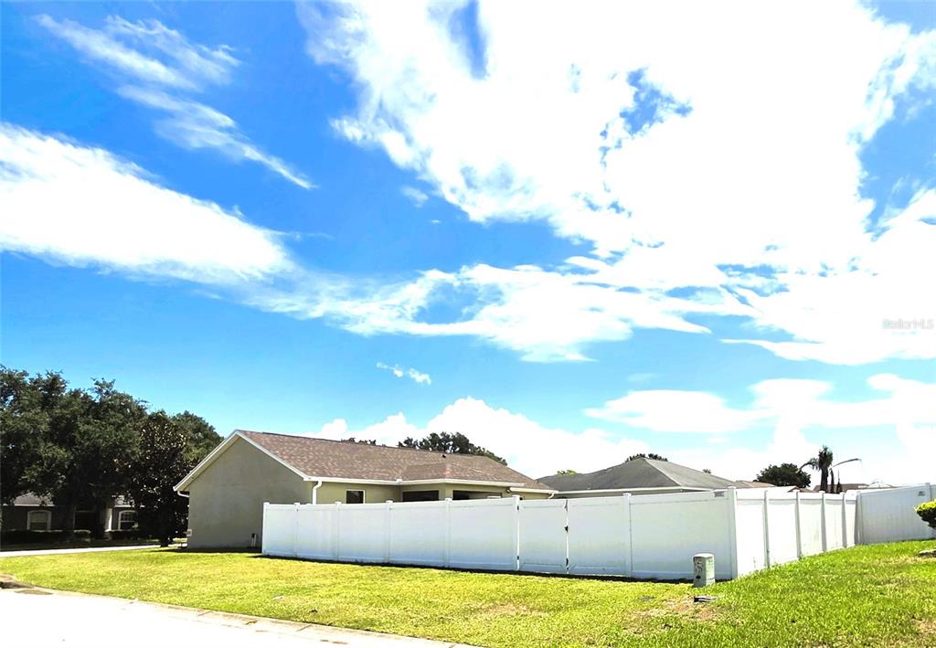 A single-story house with a white vinyl fence in the backyard under a blue sky — 2269 COUNTRY MANOR STREET, BARTOW, FL