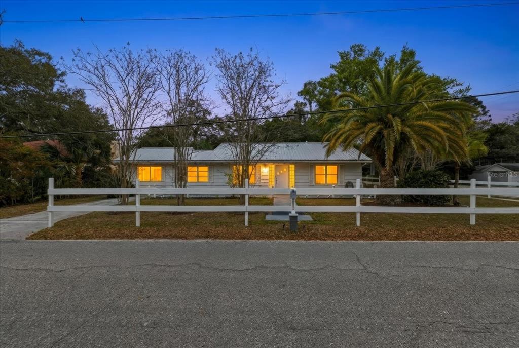 A single-story house with a metal roof sits behind a white picket fence — 1010 INDIAN BEACH DRIVE DRIVE, SARASOTA, FL