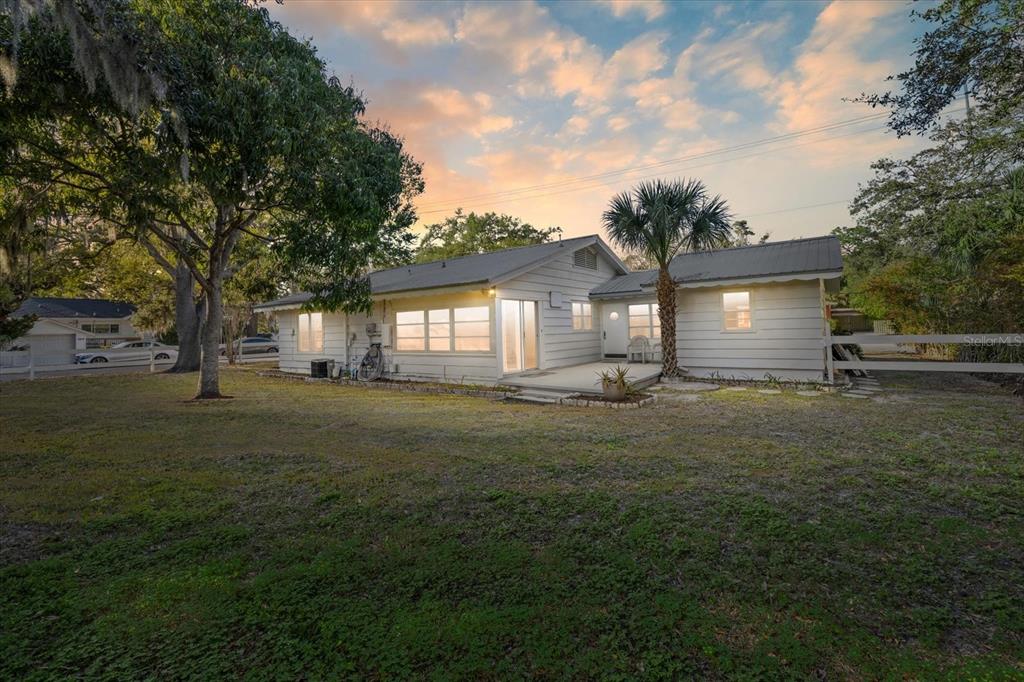 A white single-story house with a metal roof sits on a grassy lot at sunset — 1010 INDIAN BEACH DRIVE DRIVE, SARASOTA, FL
