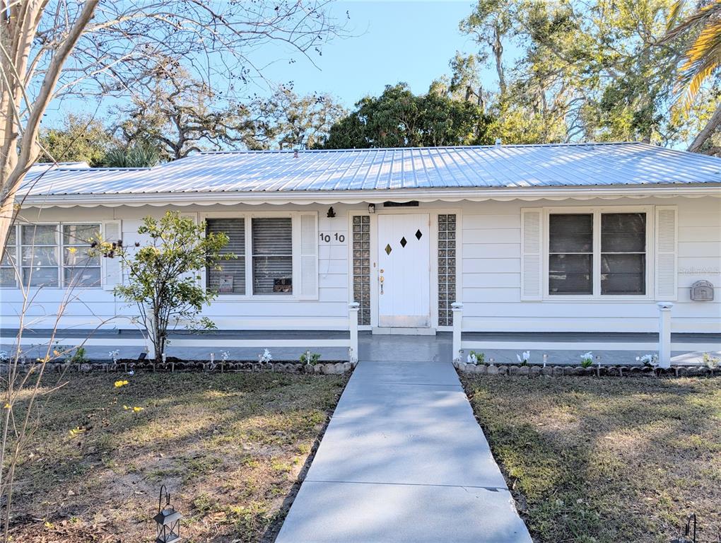 A single-story white house with a metal roof and a concrete walkway leading to the entrance — 1010 INDIAN BEACH DRIVE DRIVE, SARASOTA, FL