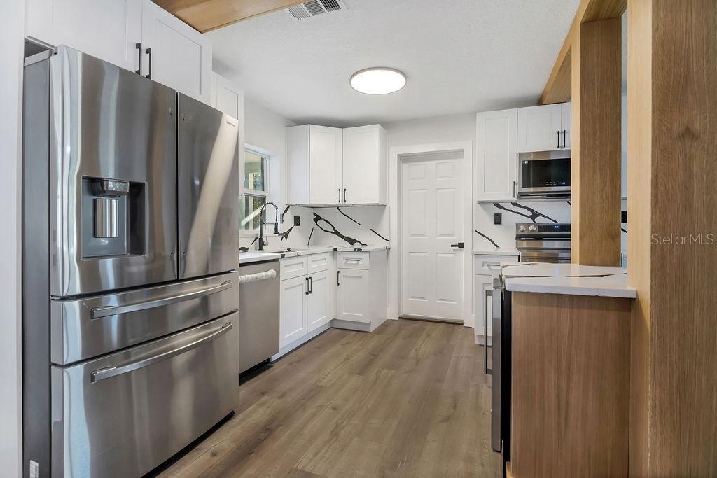 A modern kitchen features white cabinets, stainless steel appliances, and black-veined white countertops — 527 SUNRISE DRIVE, ORLANDO, FL