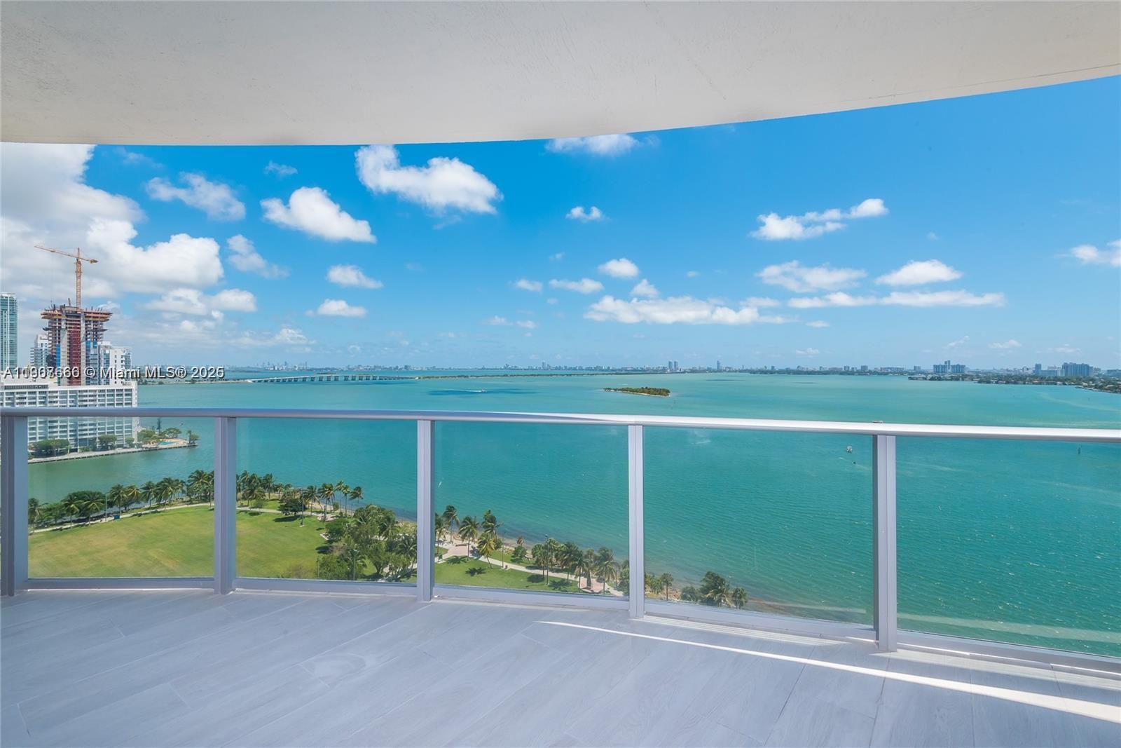 A balcony with a glass railing overlooks a park, a bay, and a distant city skyline — 488 NE 18th St # 1815, Miami FL 33132, MIAMI, FL