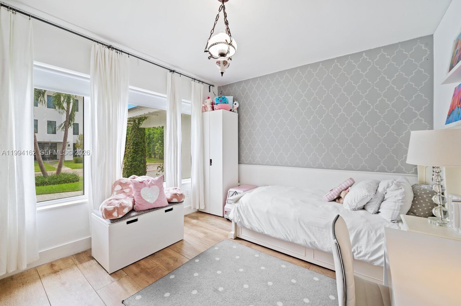 A bedroom features a twin bed, a storage bench, and a patterned accent wall — 3551 E Glencoe St, Miami FL 33133, MIAMI, FL