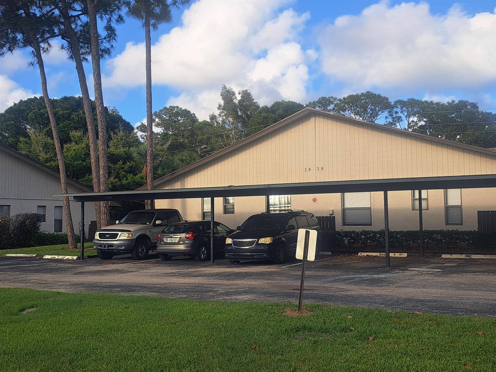 A beige apartment building with a covered parking area and three parked vehicles — 2838 Stoneway Lane, Fort Pierce FL 34982, FORT PIERCE, FL