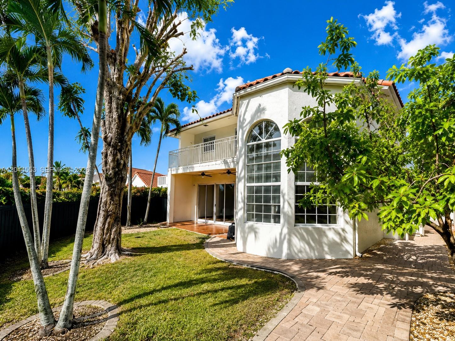 A two-story house with a white stucco exterior, arched windows, and a backyard patio area — 5132 NW 106th Ave, Doral FL 33178, DORAL, FL