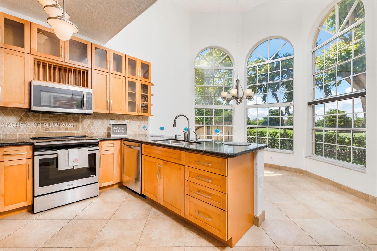 A kitchen features light wood cabinets, stainless steel appliances, dark countertops, and large arched windows — 5132 NW 106th Ave, Doral FL 33178, DORAL, FL