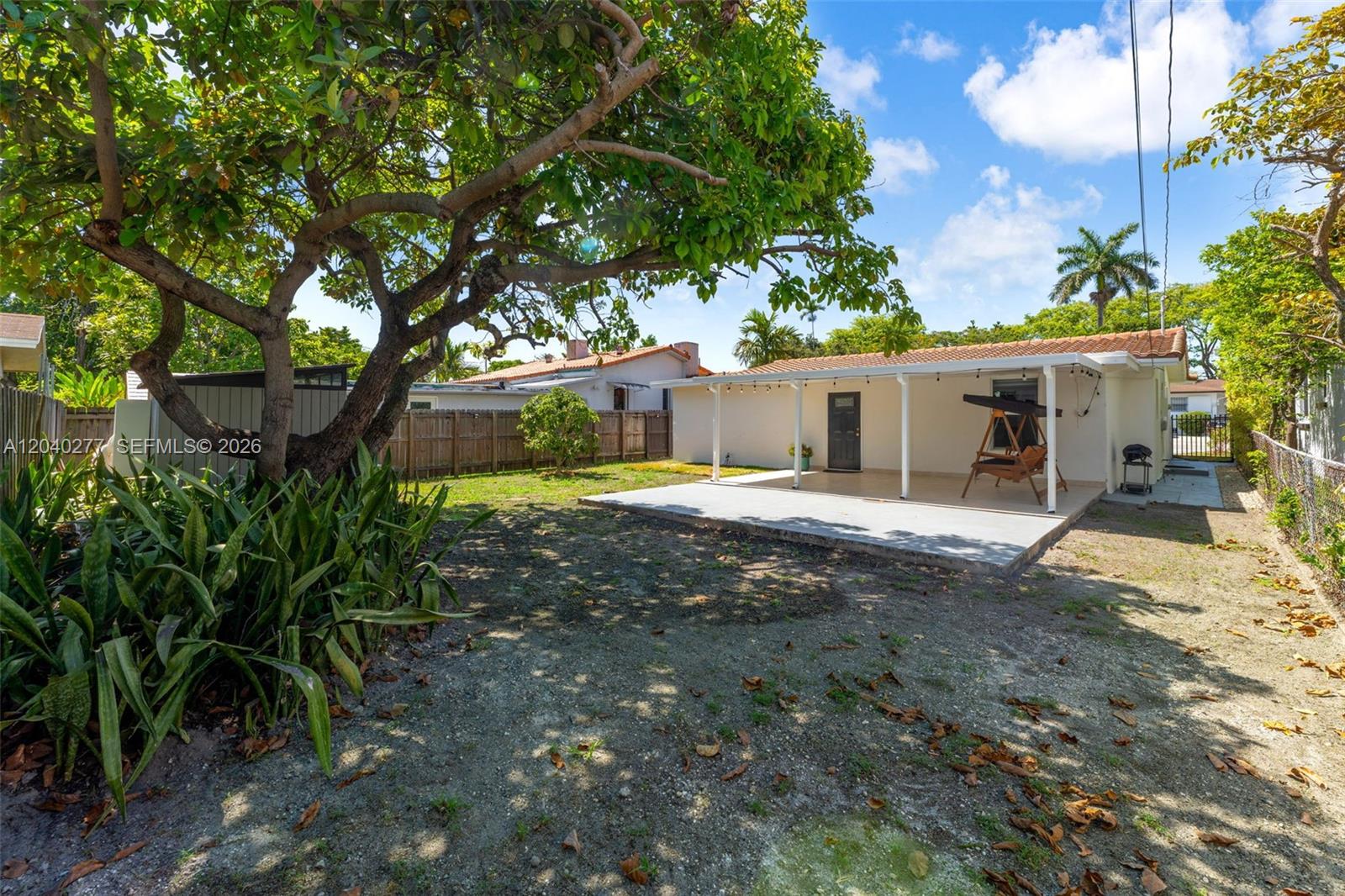 A backyard features a concrete patio, a covered porch, a large tree, and a fence — 2131 SW 17th St, Miami FL 33145, MIAMI, FL