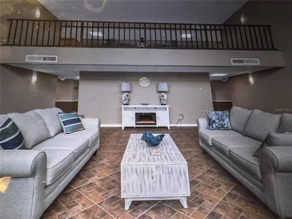 A living room features two gray sofas, a coffee table, and a fireplace console — 2290 AARON STREET UNIT 207, PORT CHARLOTTE, FL