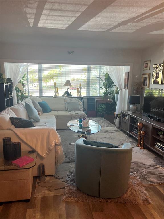 A living room features a large sectional sofa, a round glass coffee table, and television — 2290 AARON STREET UNIT 207, PORT CHARLOTTE, FL