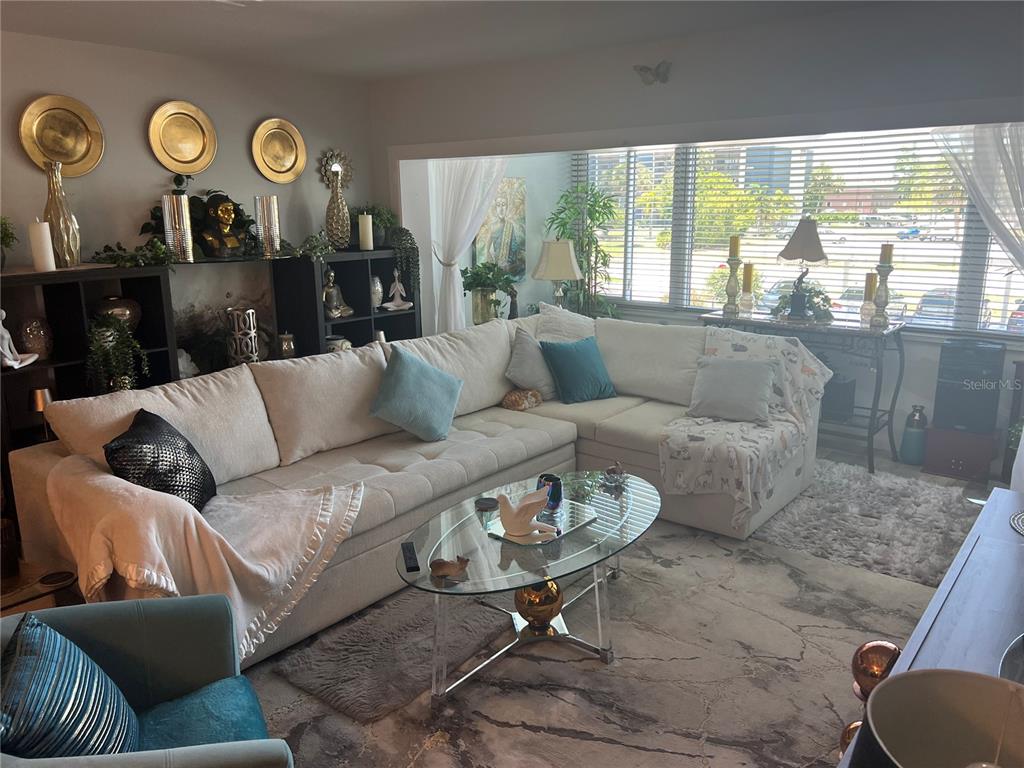 A living room features a large sectional sofa, a glass coffee table, and decorative wall plates — 2290 AARON STREET UNIT 207, PORT CHARLOTTE, FL