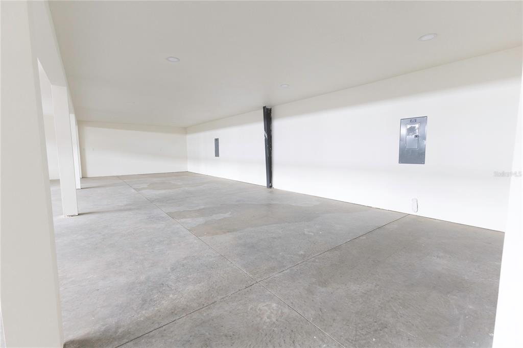 An empty garage with white walls, a concrete floor, and a mounted electrical panel — 11089 N US HIGHWAY 301 UNIT I-6,I-7, OXFORD, FL