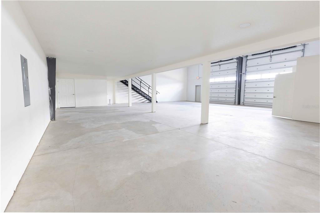 An open warehouse space with concrete floors, white walls, support columns, and two garage doors — 11089 N US HIGHWAY 301 UNIT I-6,I-7, OXFORD, FL