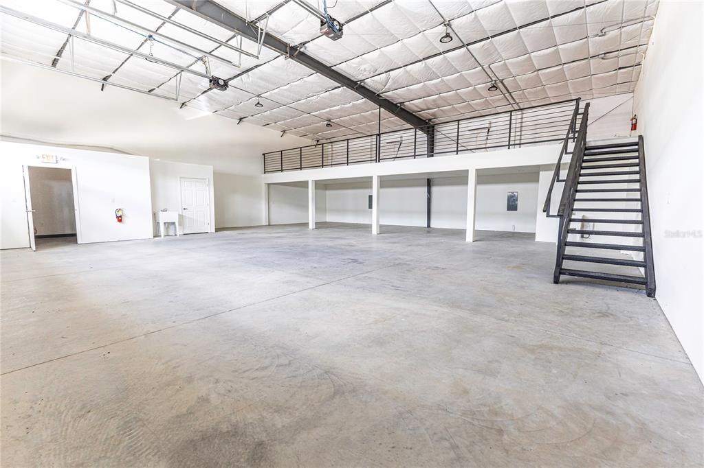An industrial warehouse space features a concrete floor, a metal staircase, and an upper mezzanine — 11089 N US HIGHWAY 301 UNIT I-6,I-7, OXFORD, FL