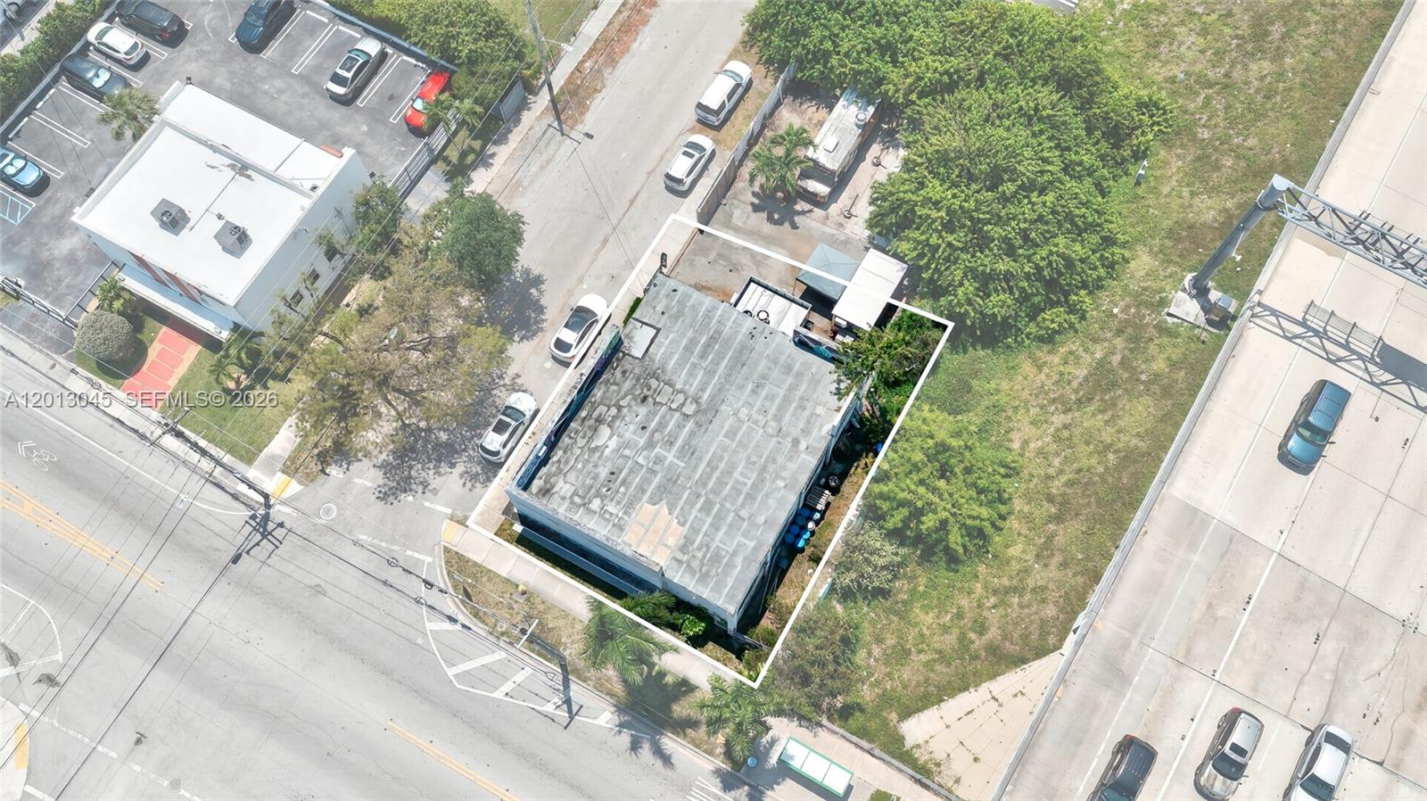 An aerial view shows a rectangular commercial building with a flat roof next to a highway — 201 NW 37th St, Miami FL 33127, MIAMI, FL