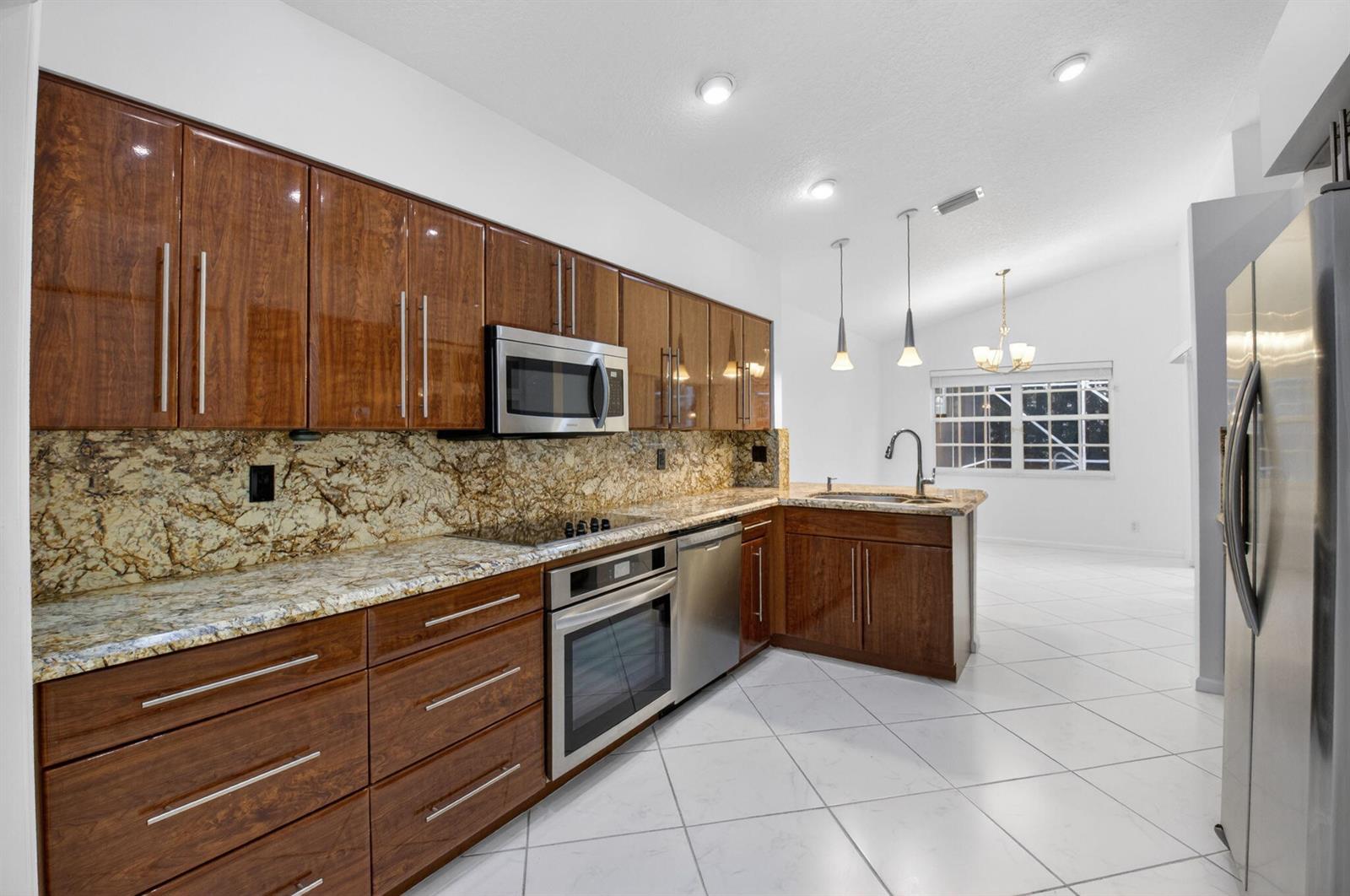 A kitchen with wood cabinets, granite countertops, stainless steel appliances, and white tile flooring — 7558 Ironbridge Circle, Delray Beach FL 33446, DELRAY BEACH, FL